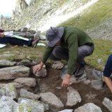 Tristan Allegro (au milieu) et son équipe fouillent l'un des abris ayant servi de bivouac sur le site du Toûno, à plus de 2750 m d’altitude. Ces investigations ont été menées entre les étés 2021 et 2023. RAMHA